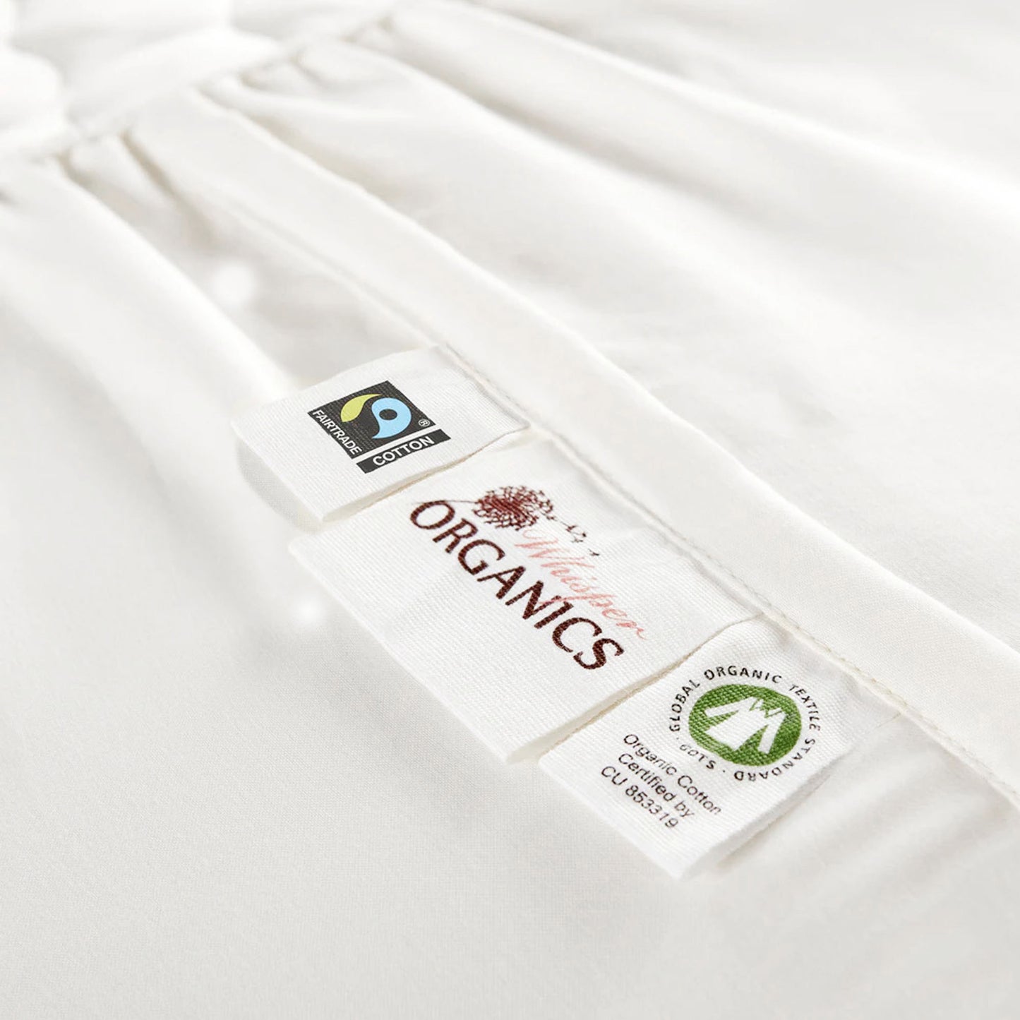 Zoomed-in view of the Whisper Organics logo next to GOTS and Fairtrade certification.
