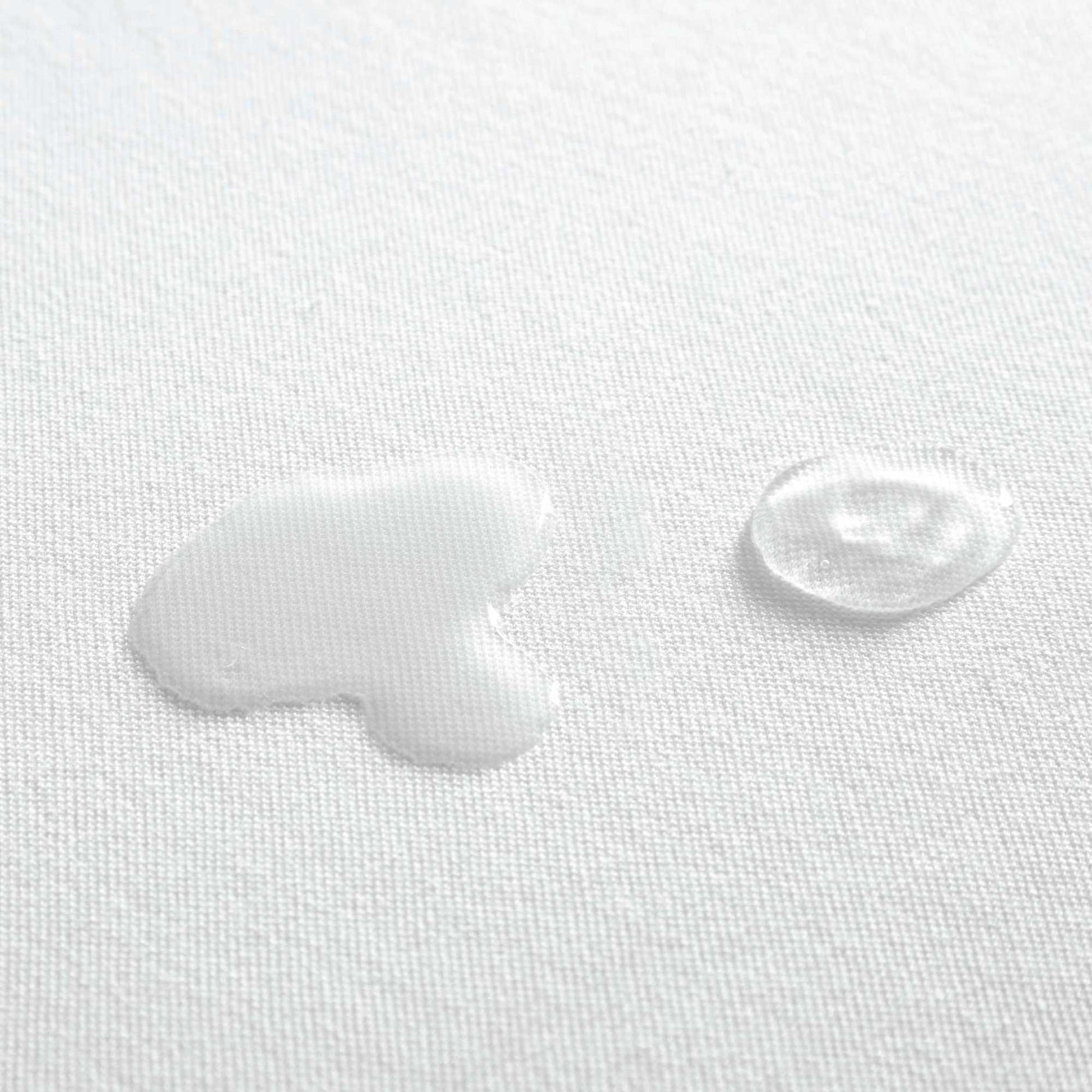 Zoomed in view of water spilled on organic cotton waterproof pique knit mattress pad, showing its liquid-repelling surface