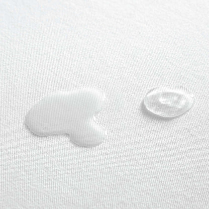 Zoomed in view of water spilled on organic cotton waterproof pique knit mattress pad, showing its liquid-repelling surface