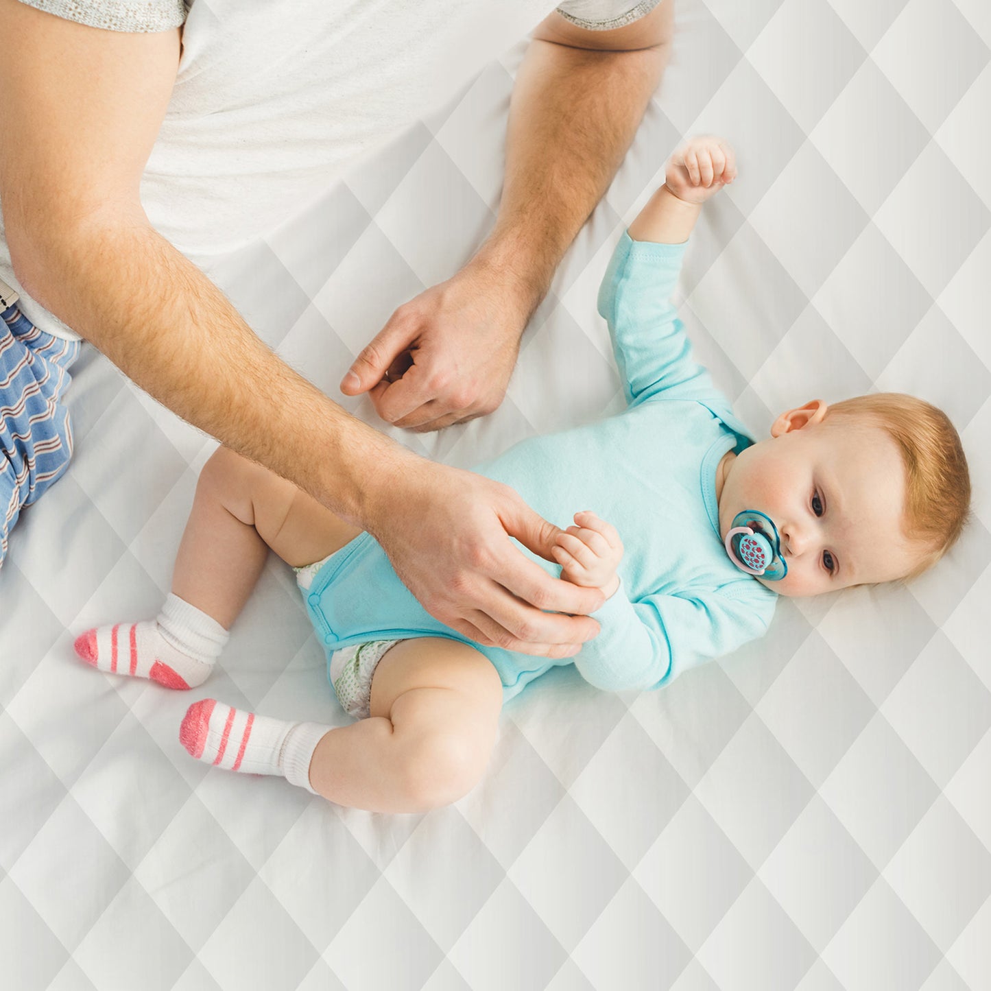 Father playing with baby son on Whisper Organics fairtrade certified organic cotton mattress cover.