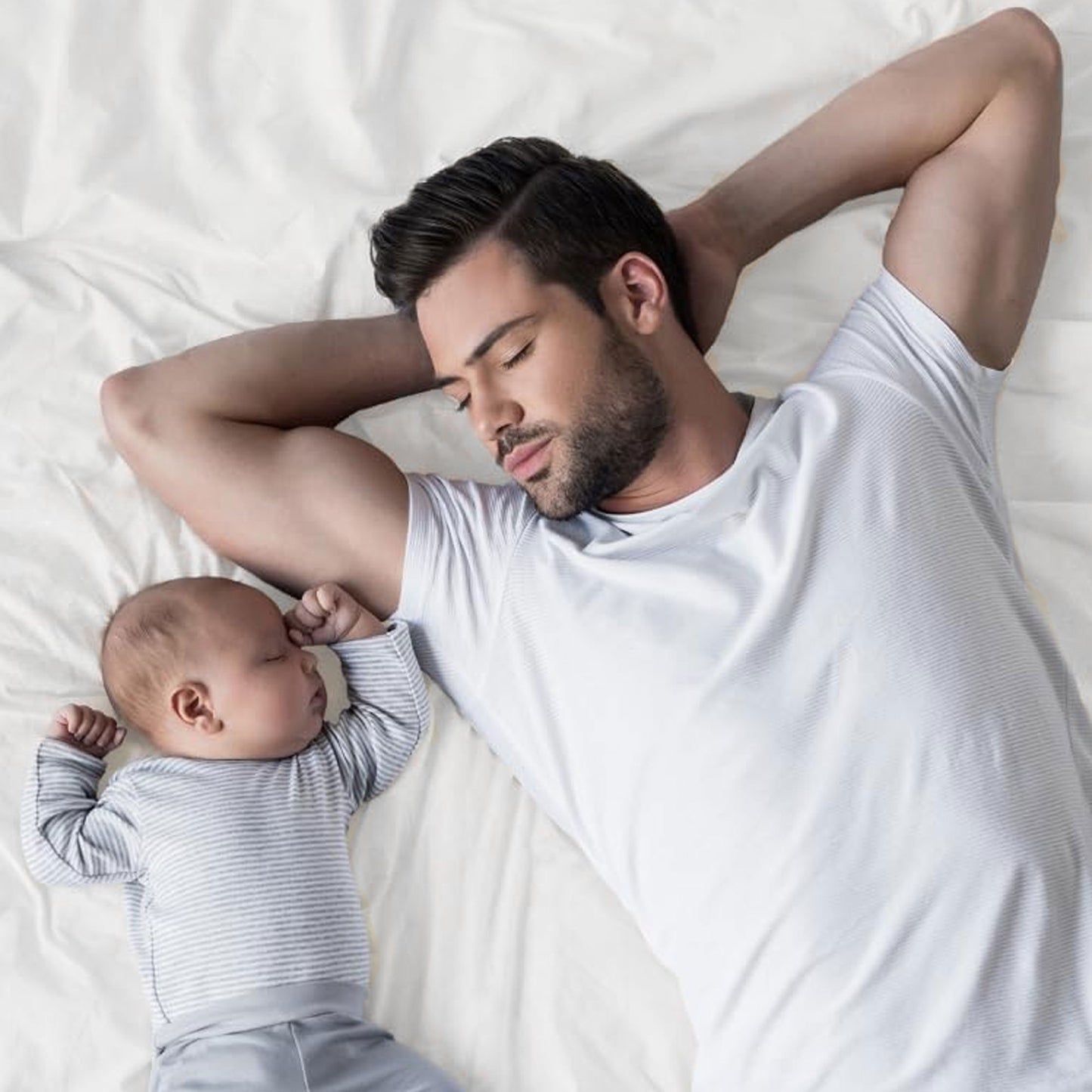 Father and baby laying down on a mattress covered with organic cotton waterproof pique knit crib mattress protector
