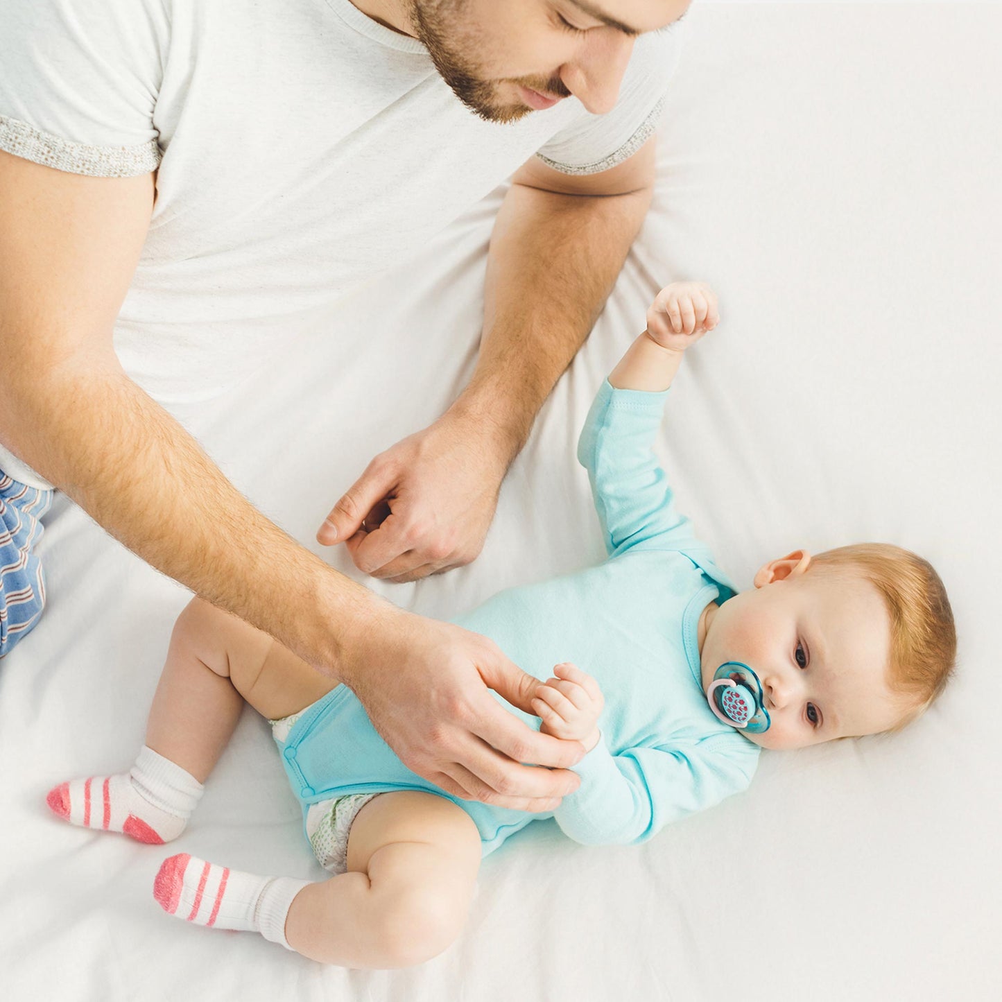 Father and baby playing on bed with fitted organic waterproof pique knit mattress cover 